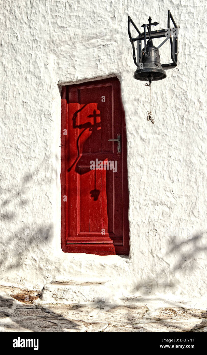 Red door in white wall with large bell Stock Photo