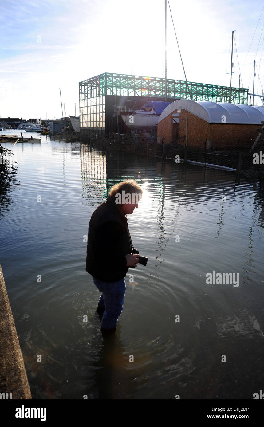 A photographer wades in the water to photograph high tide at Shoreham in West Sussex today after homes and businesses were flooded Stock Photo