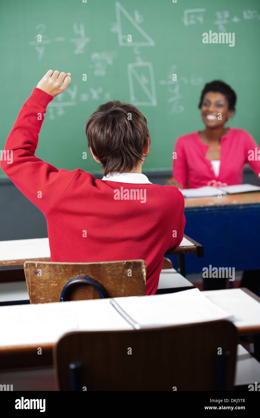 Teenage Schoolboy Raising Hand At Desk Stock Photo - Alamy
