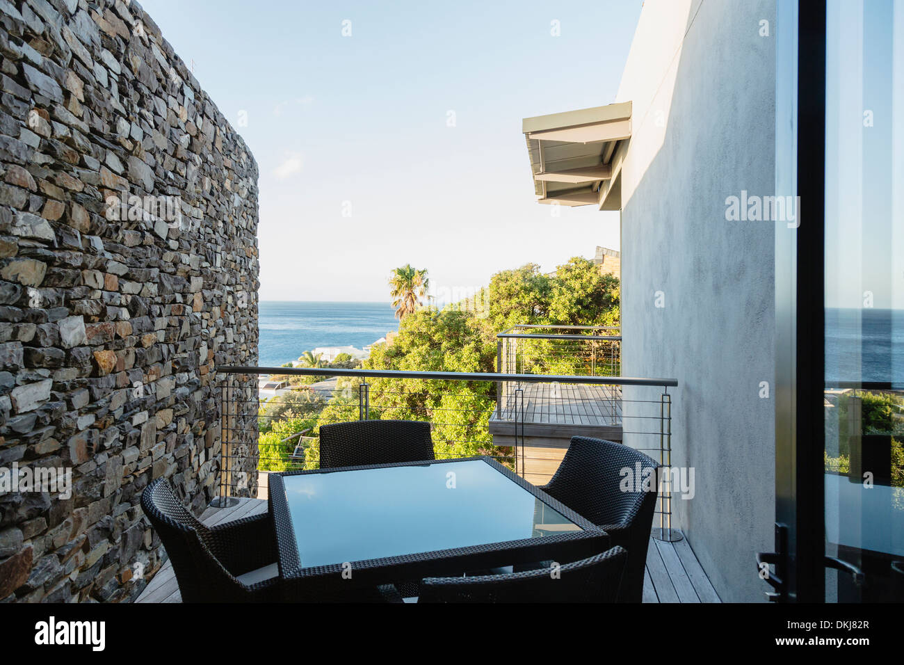 Table and chairs on luxury balcony overlooking ocean Stock Photo