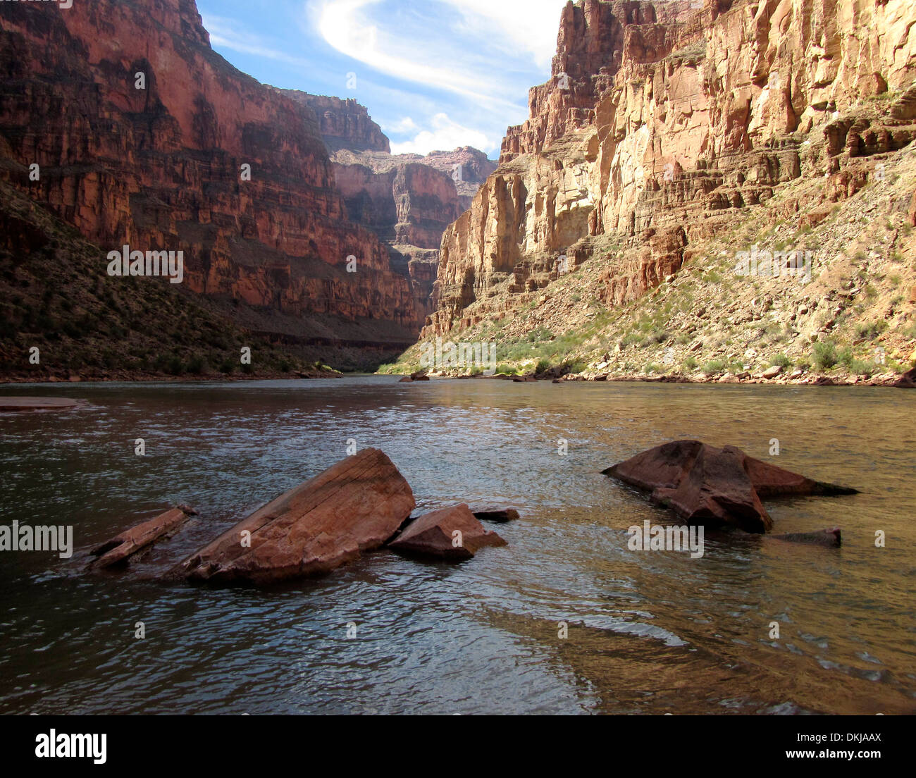 Calm water, rocks, and beautiful red and yellow cliff walls in the Grand Canyon. Stock Photo