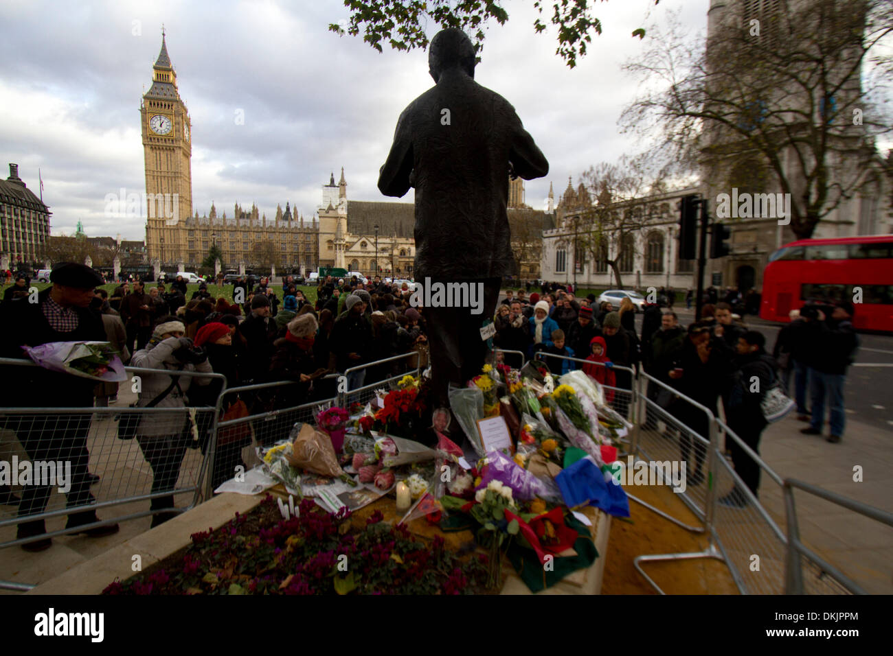 London UK. 6th December  2013. People pay their respect outside the  statue to  former South Africa 1918-2013 president Nelson Mandela in Parliament Square Westminster who died yesterday aged 95. Nelson Mandela became the first black president who was jailed after he campaigned against Apartheid and a racially divided South Africa Credit:  amer ghazzal/Alamy Live News Stock Photo