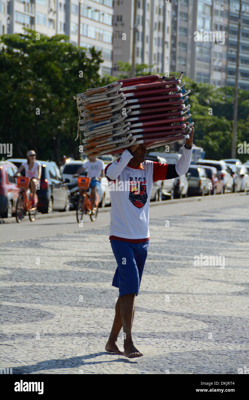A deck chair owner, carrying a stack of beach deck chairs onto