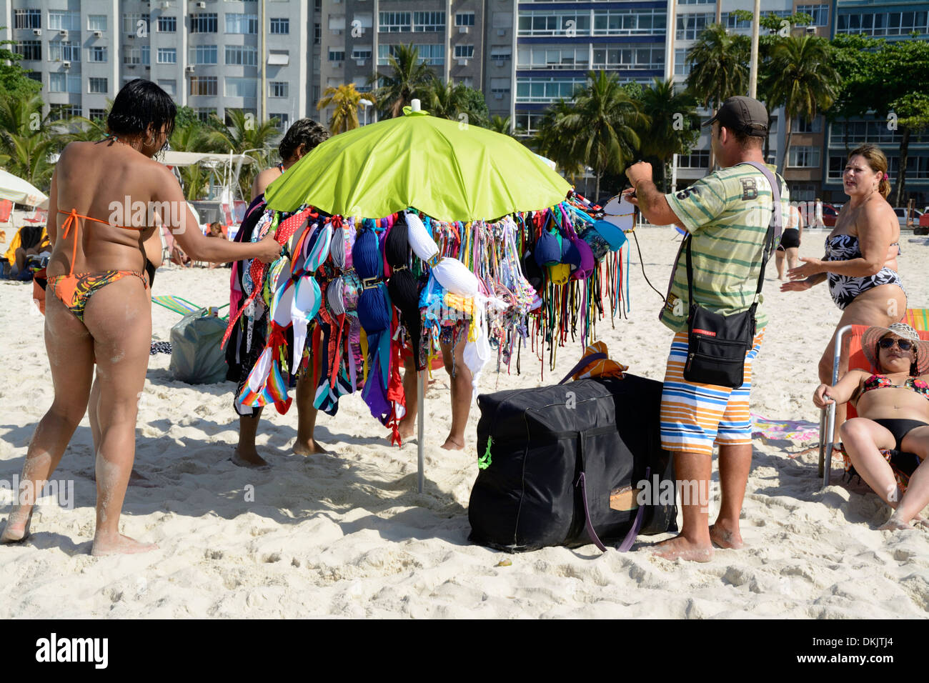 A beach hawker carrying his umbrella full of Brazilian bikinis for sale