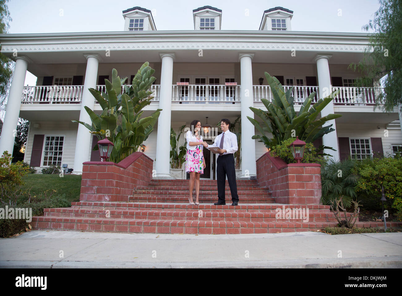 Man and woman shaking hands on front steps of a large house Stock Photo ...
