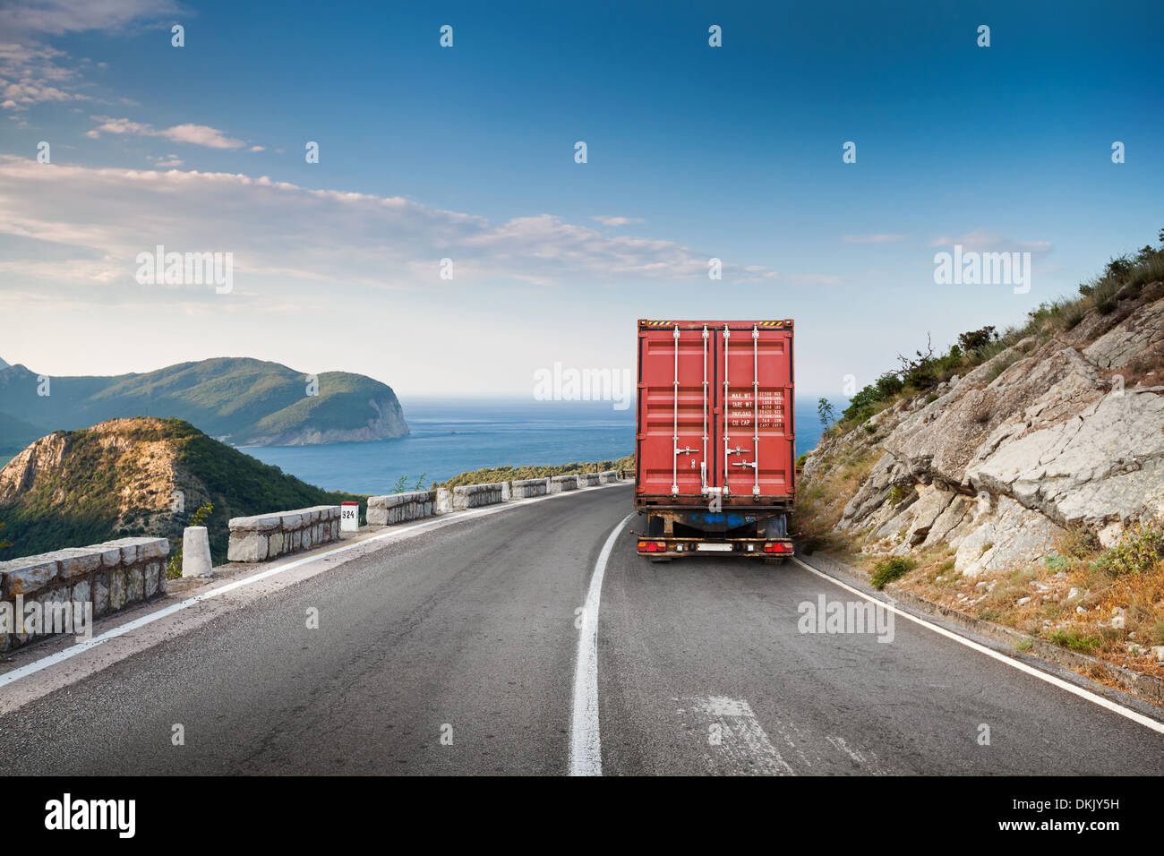 Cargo truck on the mountain highway with blue sky and sea on a background Stock Photo