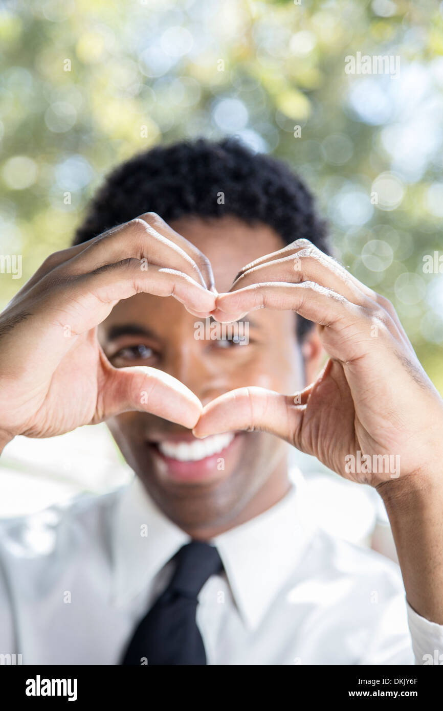 Professional young man folding hands into heart shape Stock Photo