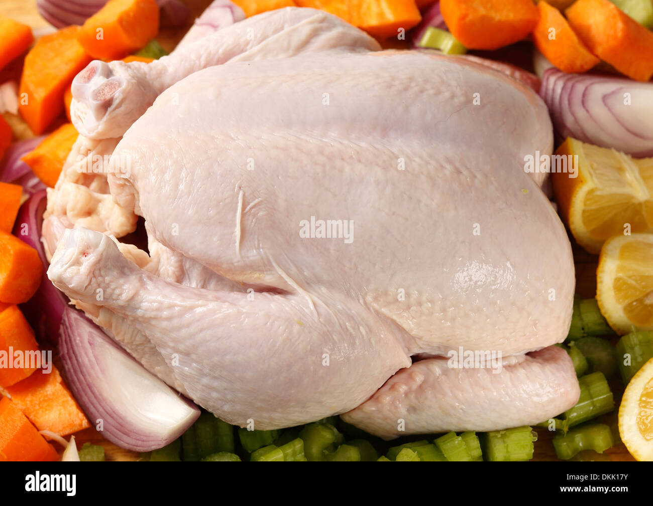 Raw, fresh, whole chicken and vegetables to cook with it in a stew or pot-roast Stock Photo
