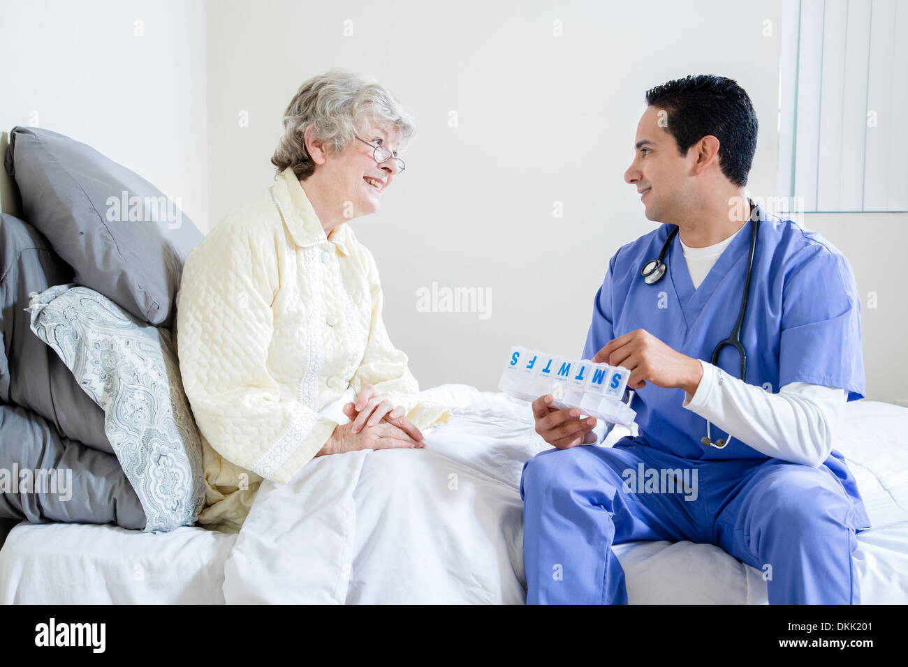 Male nurse helping elderly patient with her pills Stock Photo