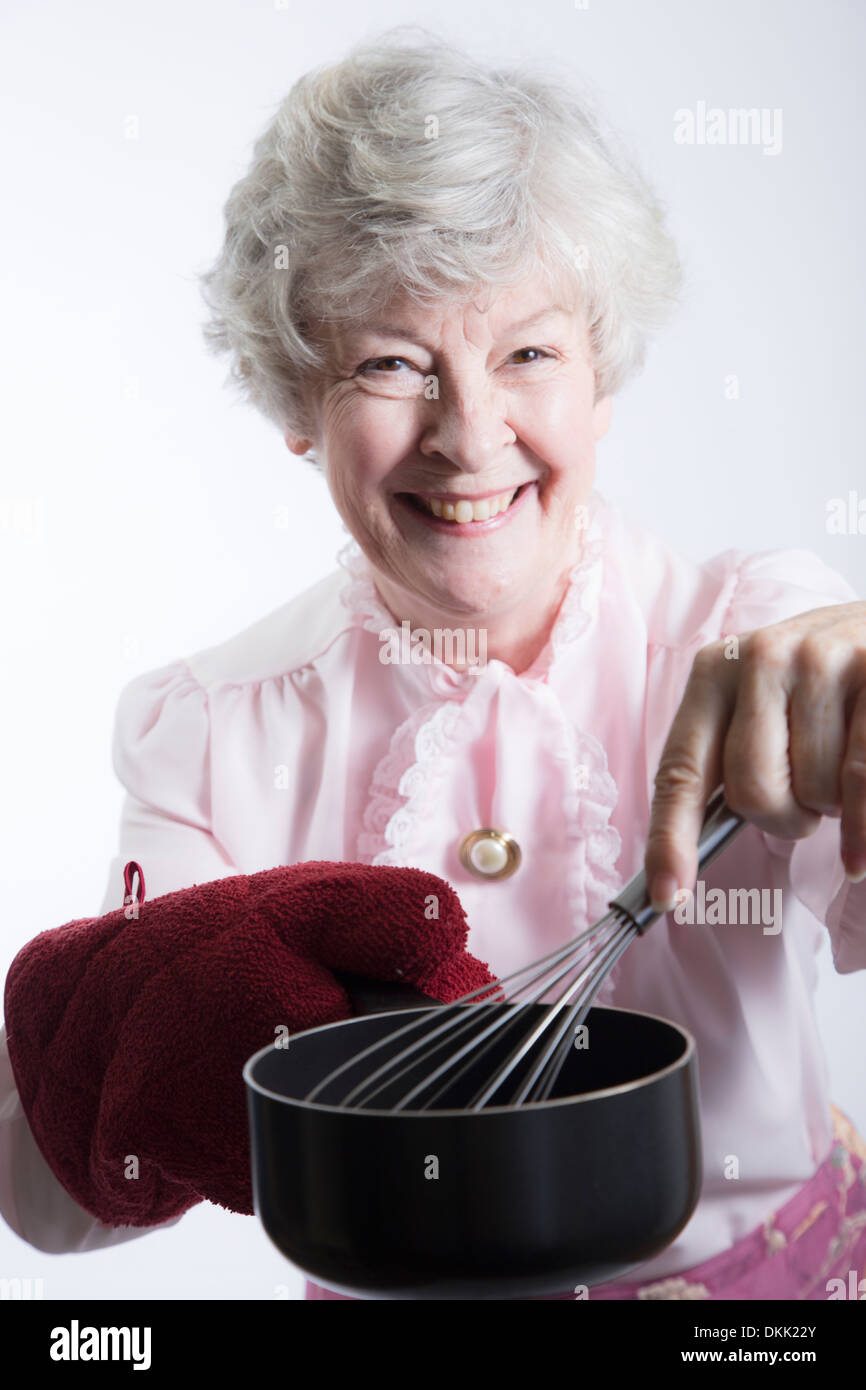 Elderly woman with pot and wire whisk Stock Photo