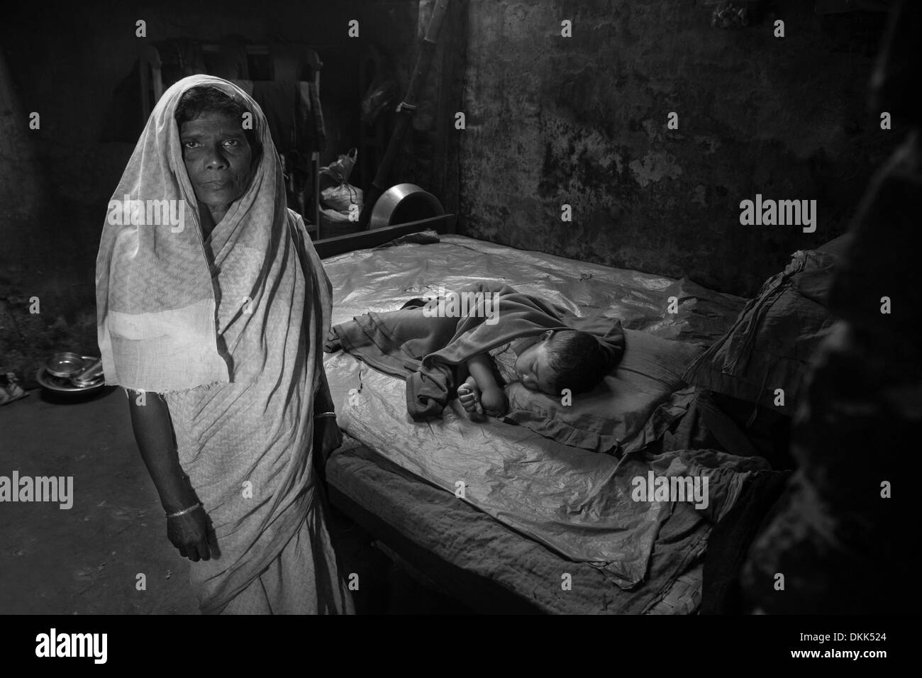 Rangpur, Bangladesh. 30th March, 2013. A Bihari mother stands next to her sleeping grandchild in Bangladesh. Her home was recently damaged from a fire but she has no money to repair it. 42 years after the 1971 war there are still an estimated 600,000 Biharis (also known as 'stranded Pakistanis') living in Bangladesh - mostly still in camps. © Hanna Adcock/ZUMA Wire/ZUMAPRESS.com/Alamy Live News Stock Photo