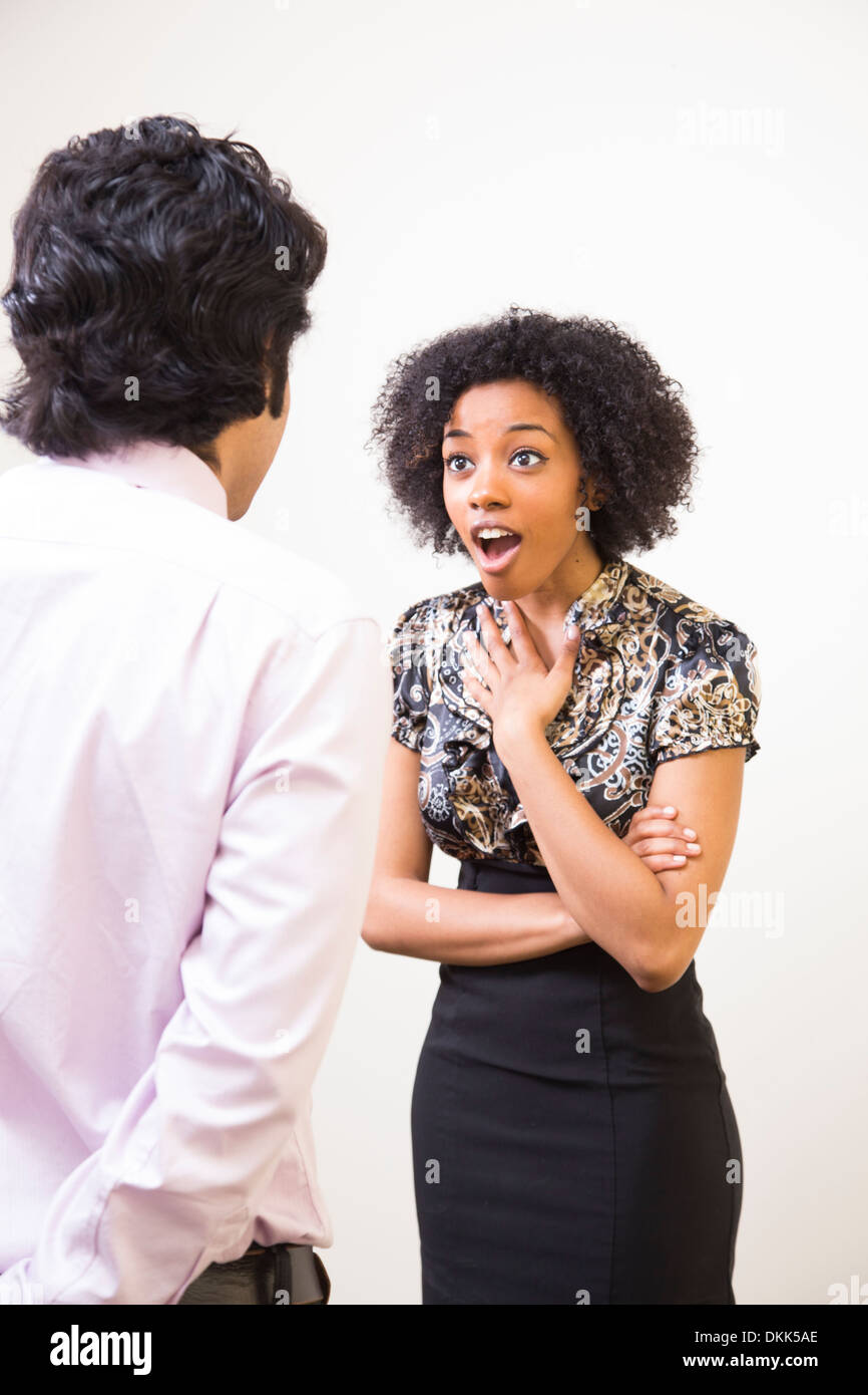 Young woman looking shocked talking to business man Stock Photo