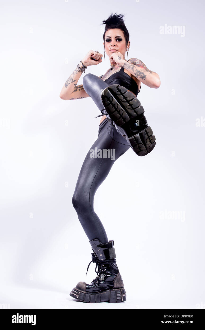 Tattooed punk girl in leather boots on white background Stock Photo