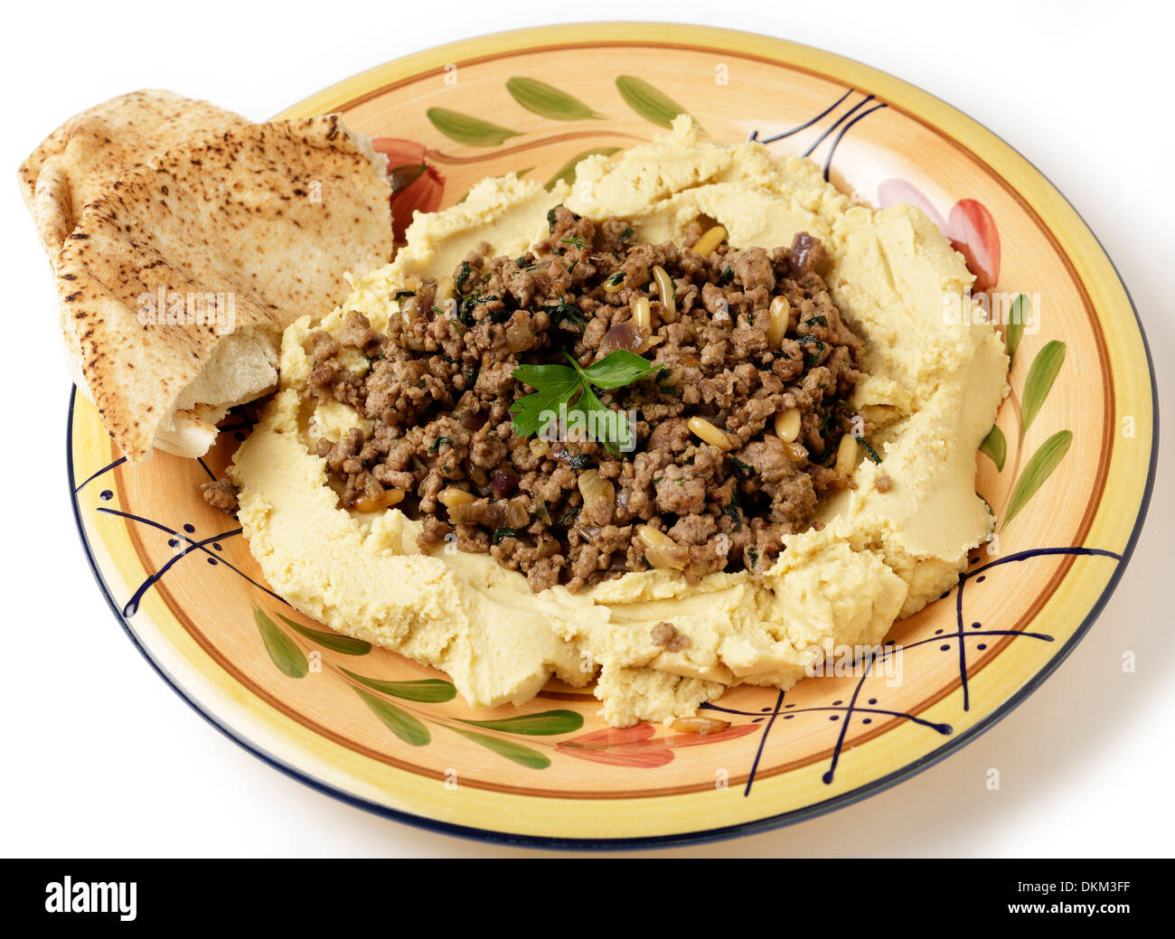 A plate of hummus chickpea dip filled with fried lamb mince, onion, pine nuts and parsley, known as hummus bil lahme. Stock Photo