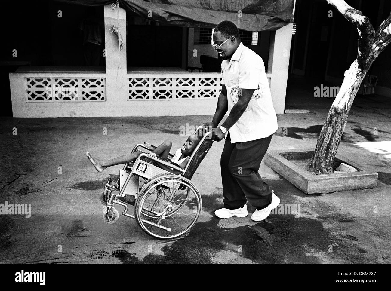 Nov. 19, 2001 - Kingston, Jamaica - Father Peter Gitumbu, a missionary priest from Kenya, brightens the day of a disabled child at Mustard Seed Communities in Kingston, Jamaica, with a spin around the courtyard. The home, which cares for children whose special needs are greater than their families can provide, is often a heartbreaker for visitors. Although many of the children cann Stock Photo