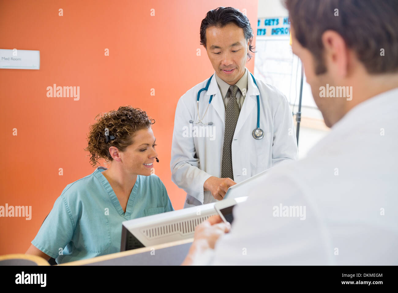 Medical Team Using Digital Tablet While Patient Standing At Rece Stock Photo
