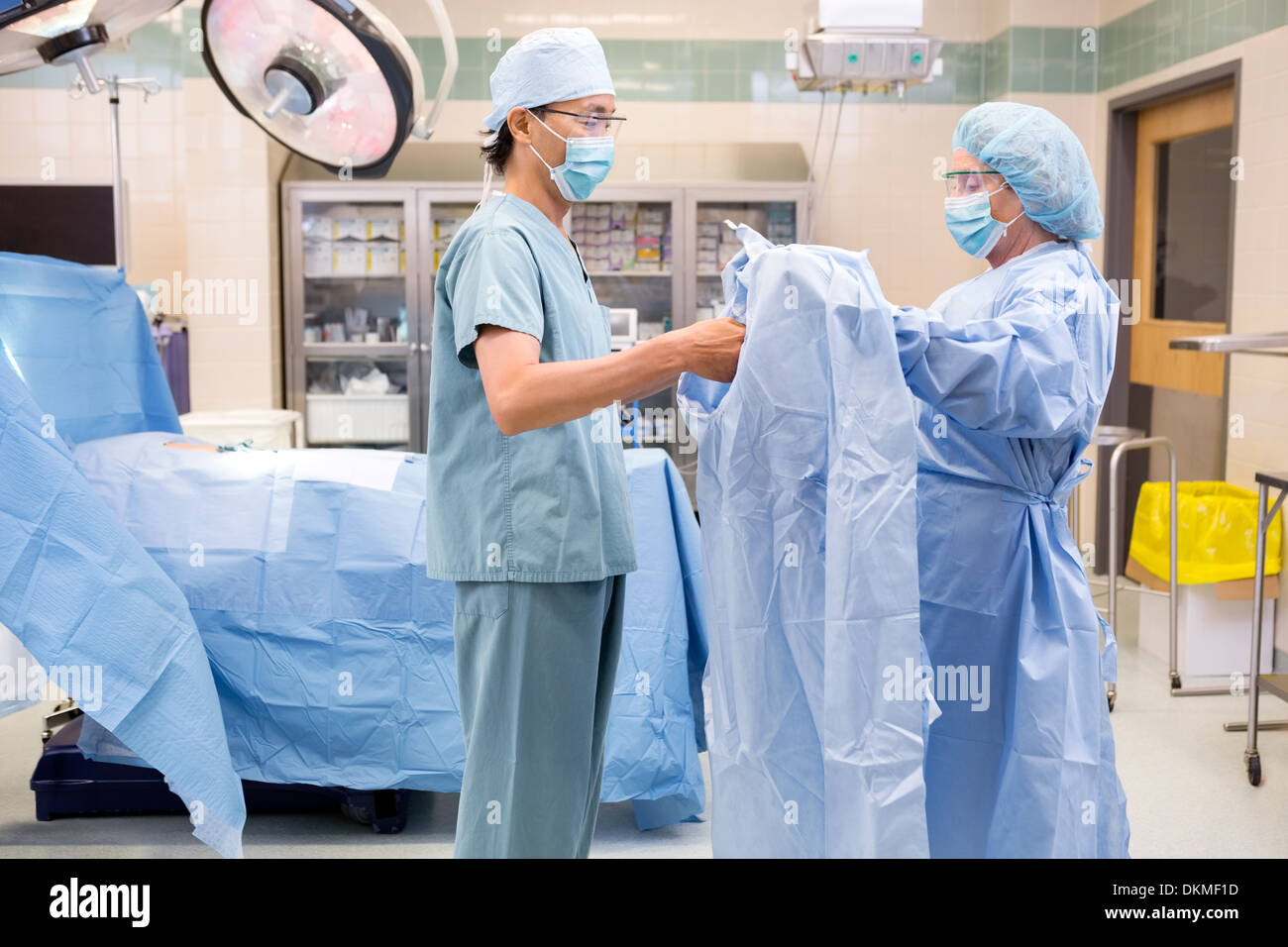 Scrub Nurse Assisting Surgeon with Gown Stock Photo