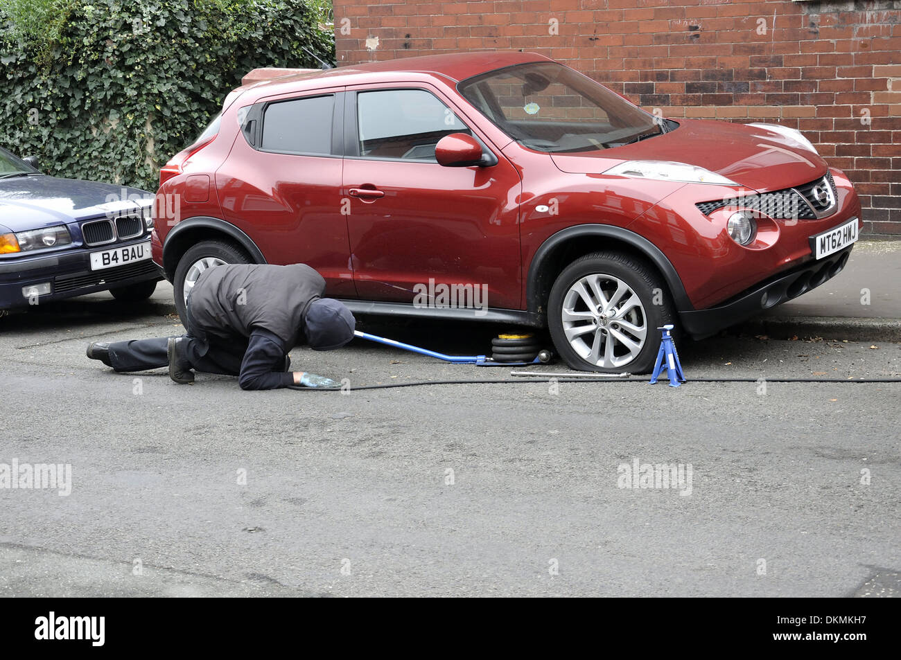 Kwik fit tyre fitter placing air jack to lift vehicle with puncture off