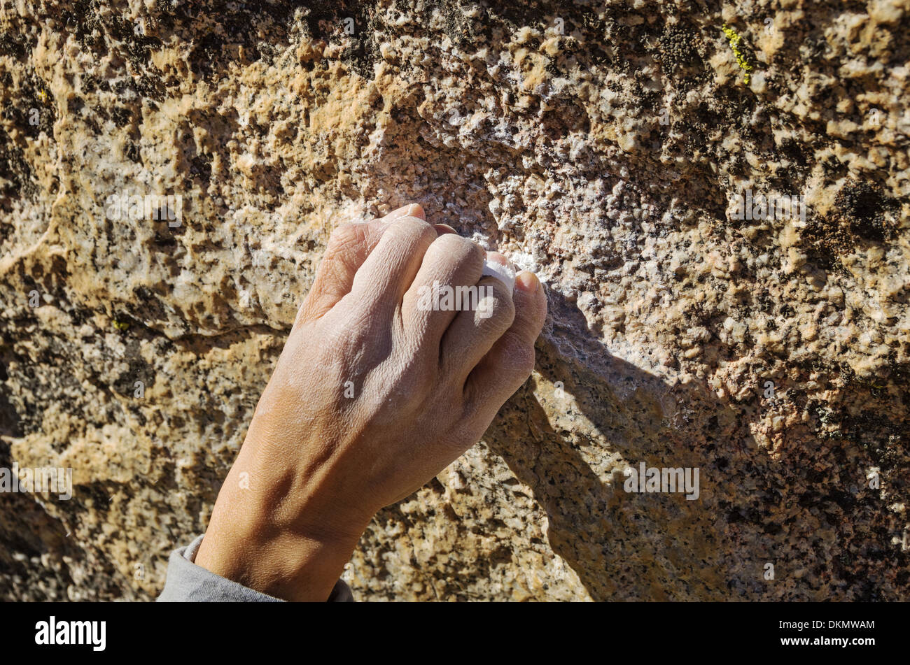 a woman climber hand grabbing a small rock hold with a crimp grip Stock Photo