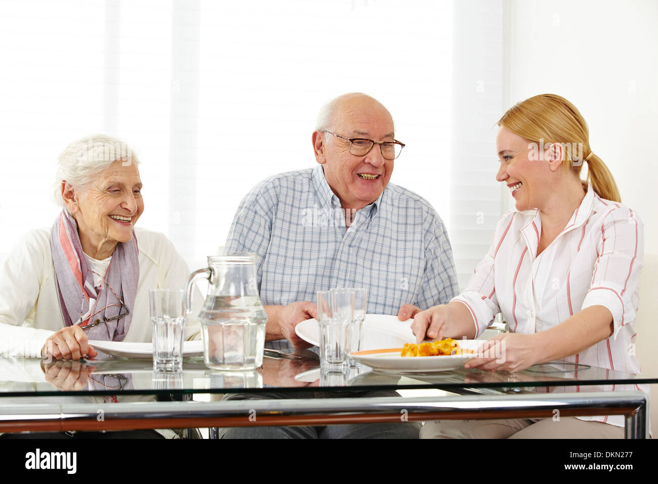 Happy family with senior couple eating lunch at table Stock Photo