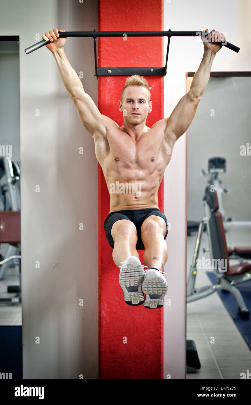 Blond attractive young man hanging from gym equipment looking at camera Stock Photo Alamy