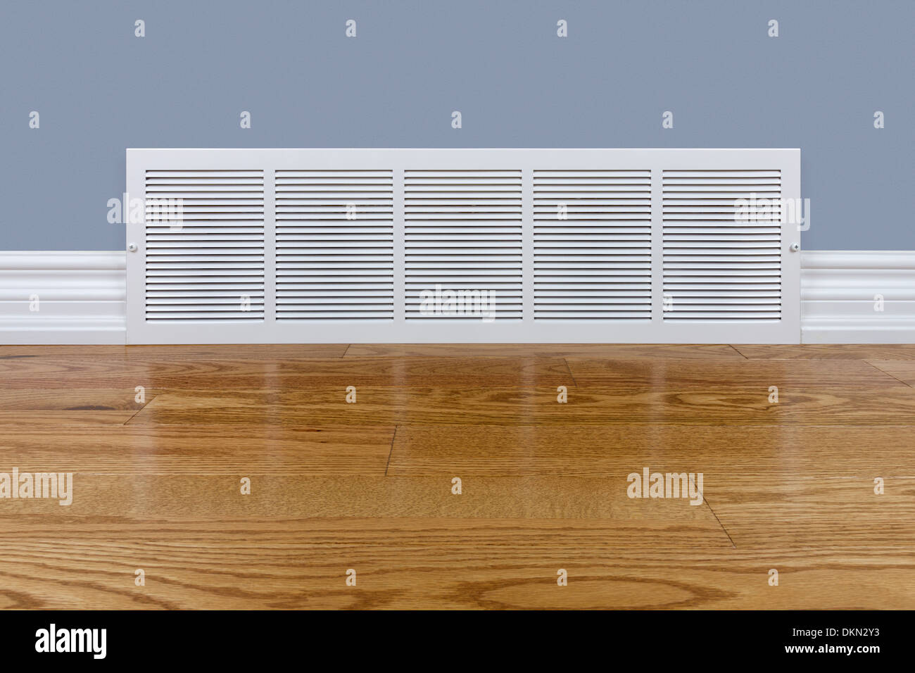 Wall cold air return grille sitting on hardwood floor Stock Photo