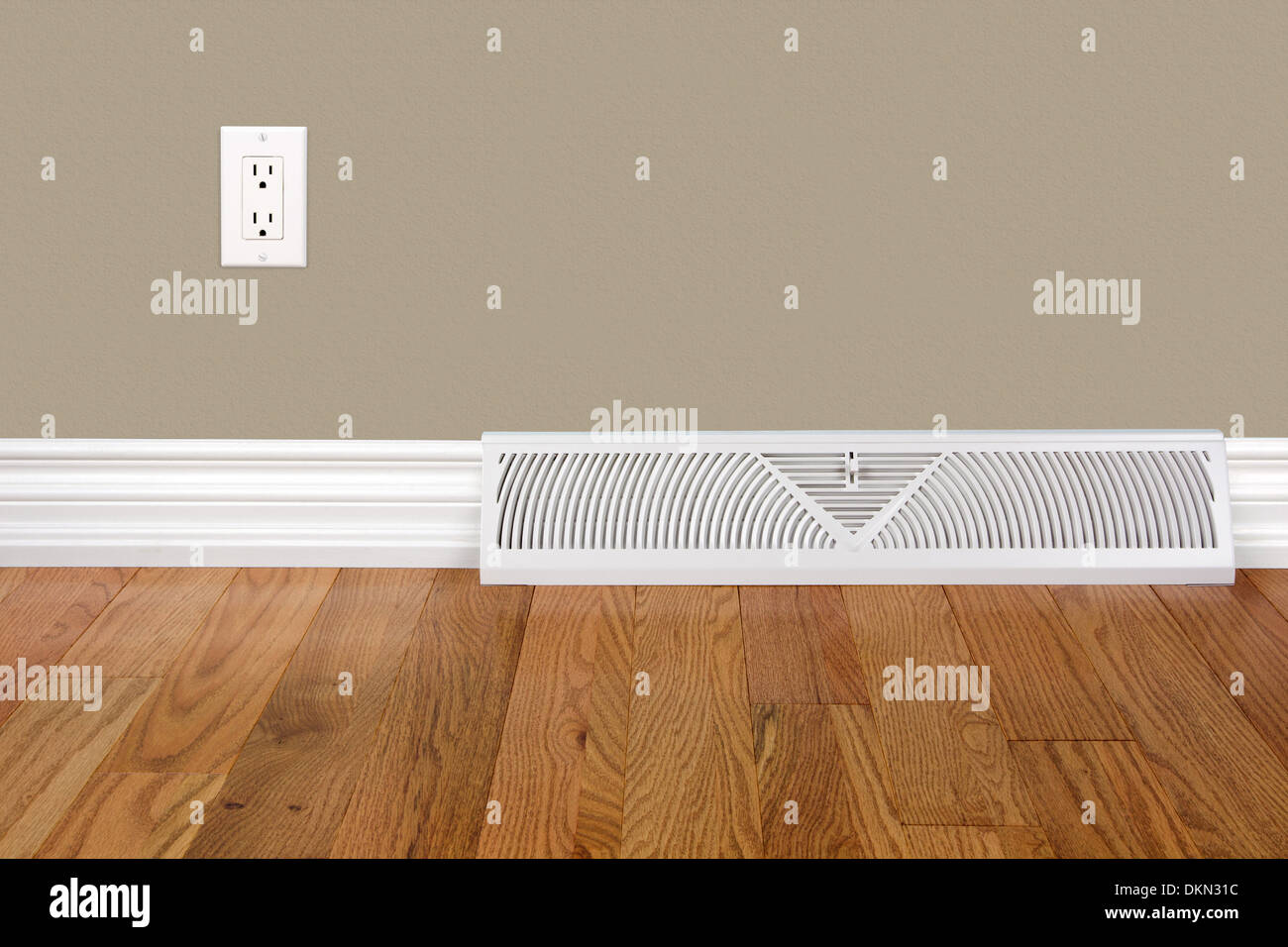 Bedroom wall with baseboard, heating register, electrical outlet and hardwood floor Stock Photo