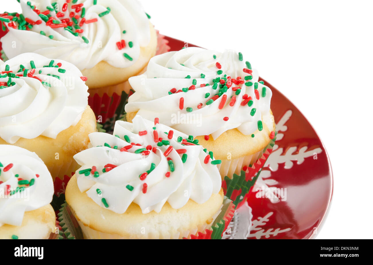 Holiday cupcakes with vanilla frosting and red and green sprinkles, served on a red holiday plate on white background. Stock Photo