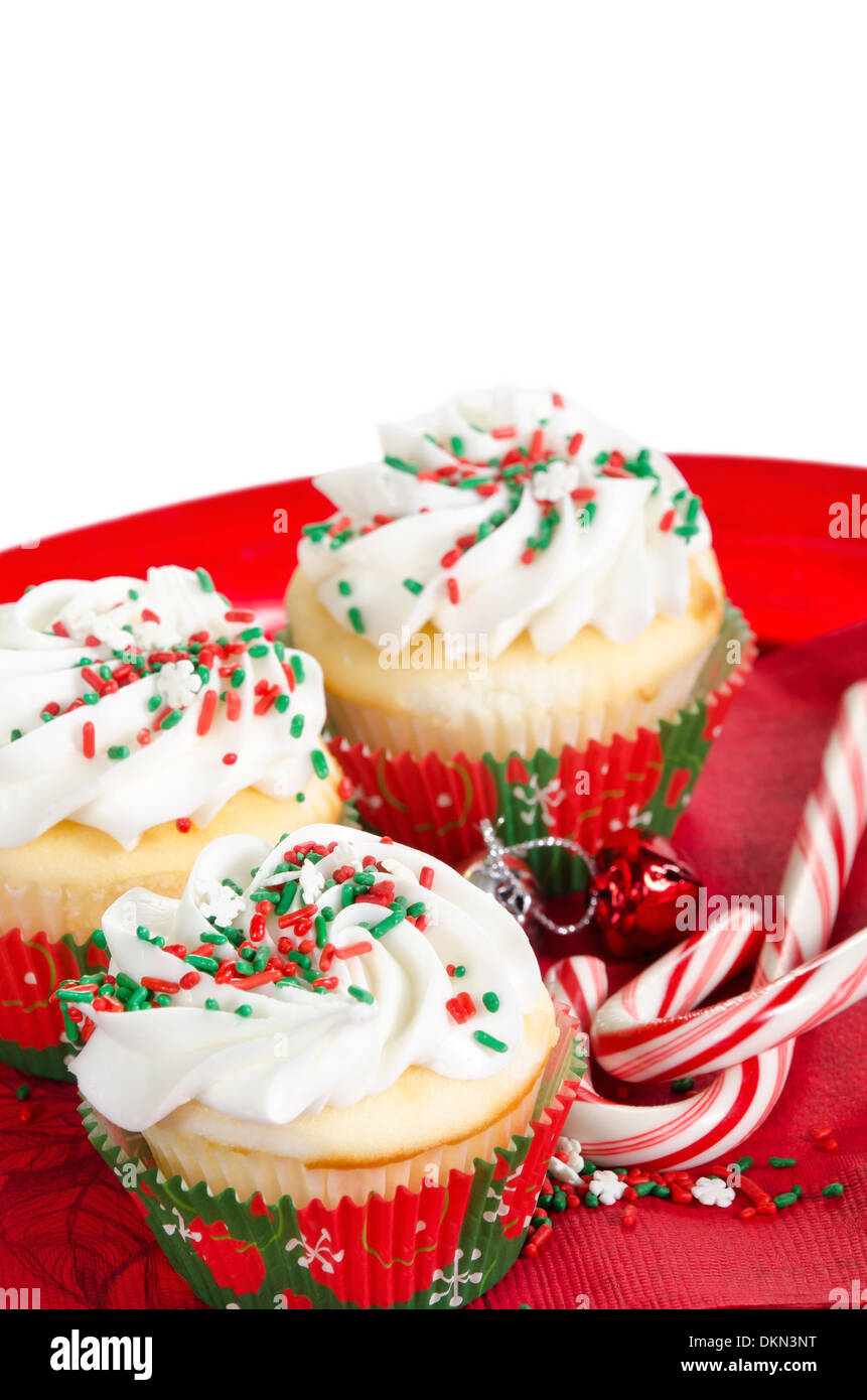 Holiday cupcakes with vanilla frosting and red and green sprinkles, served on a red holiday plate on white background. Stock Photo