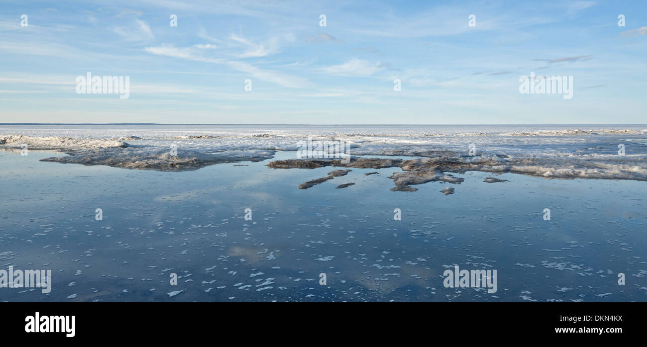 Open water reveals itself as a frozen lake thaws under the early spring warmth. Lake Simcoe, Georgina, Ontario, Canada. Stock Photo