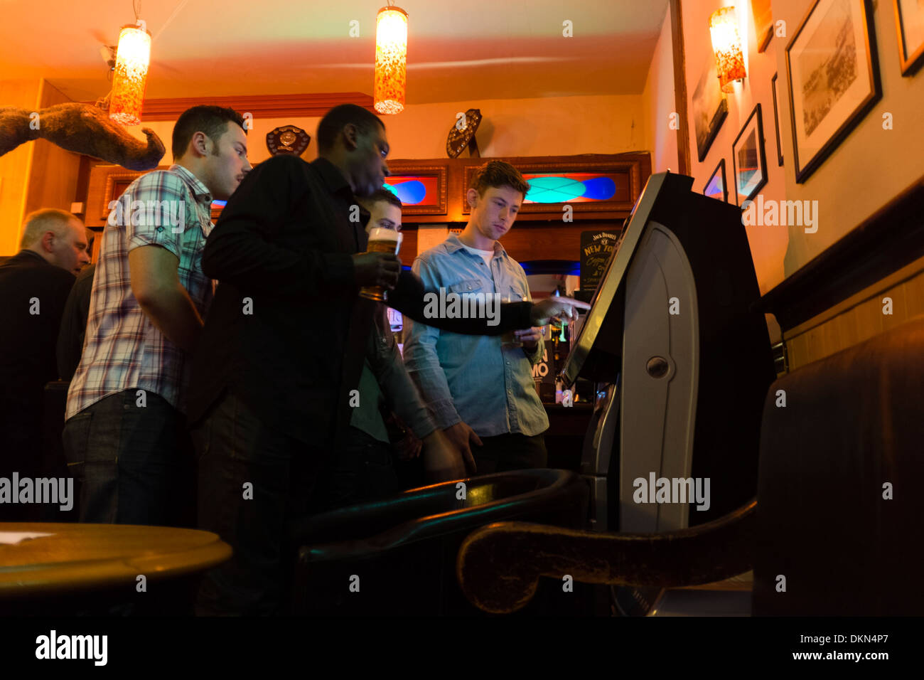 A group of young men playing on a quiz machine in the Castle Hotel pub, Aberystwyth UK Stock Photo