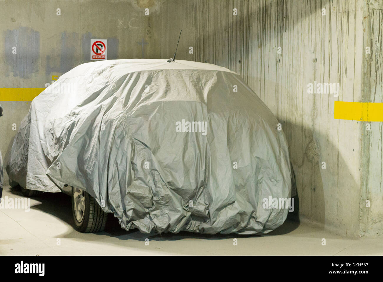 Car with cover sheet for sunlight, rain and dust protection in a parking lot Stock Photo