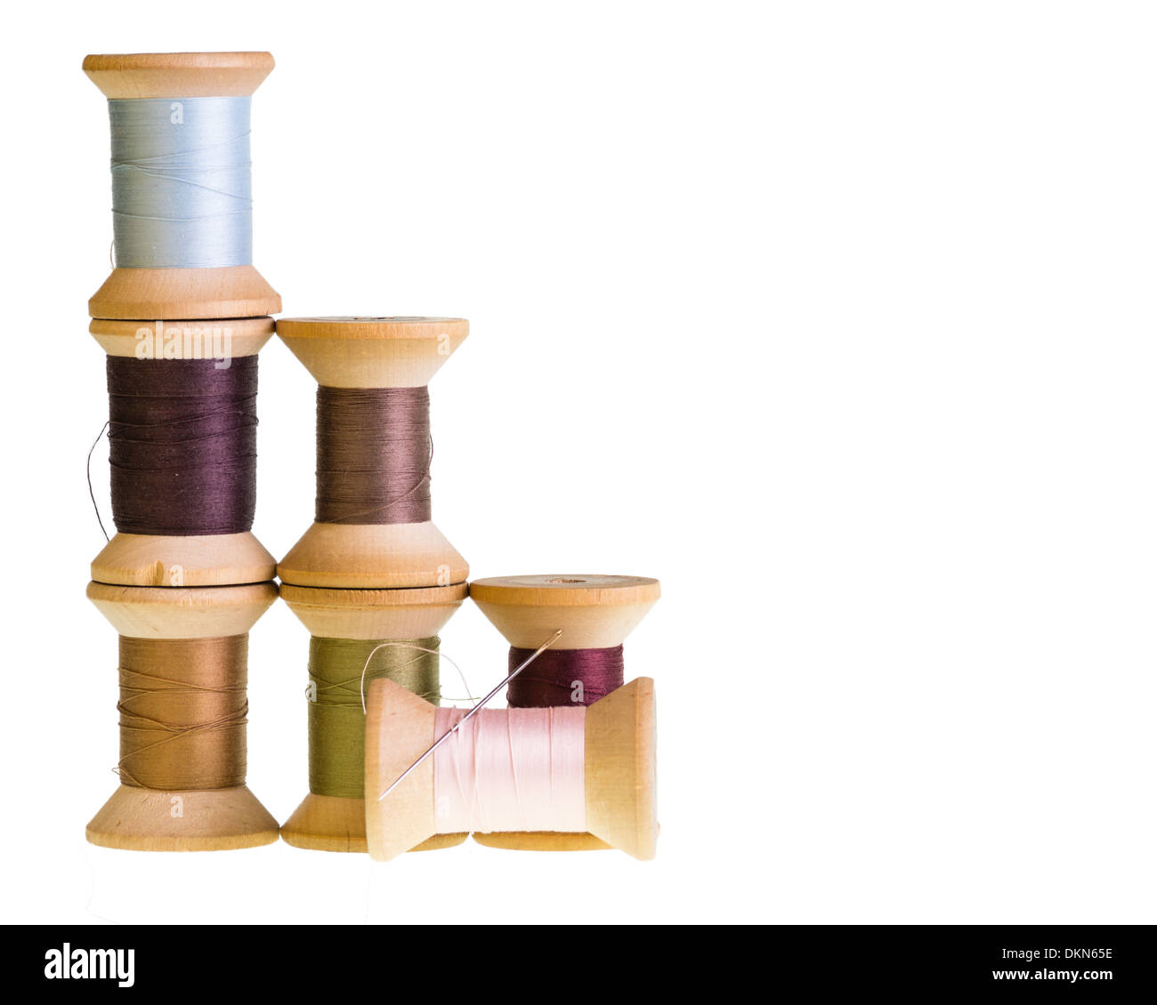 Wooden spools of sewing thread with a needle isolated on white Stock Photo
