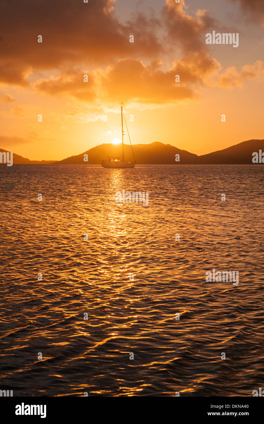 Sunset over the caldera at Totoya, with a yacht at anchor off the village of Tovu. Totoya, southern Lau Islands, Fiji. Stock Photo