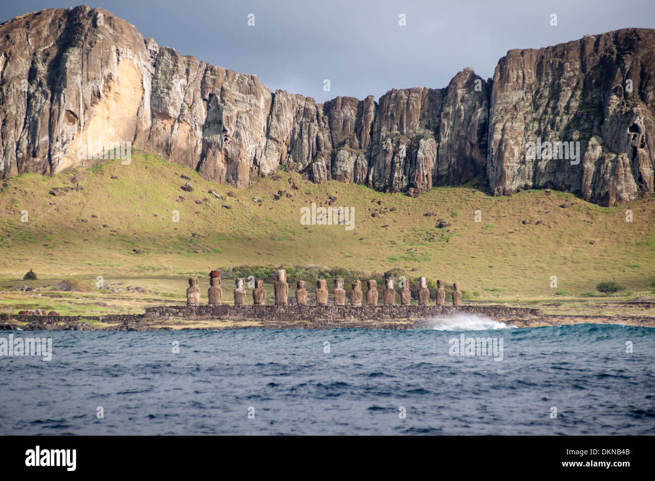 Rockface of Rano Raraku volcano and Ahu Tongariki with its 15 moai (carved stone statues) Hotuiti Bay, SE Easter Island Stock Photo