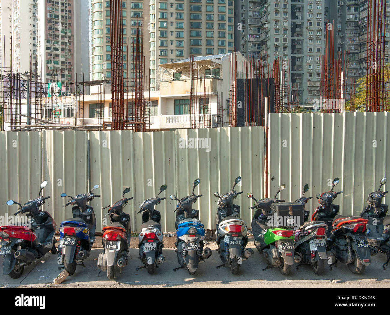 Motorcycles parked in front of a construction site, old homes replace by new skyscrapers, at booming Coloane of Macau, China Stock Photo