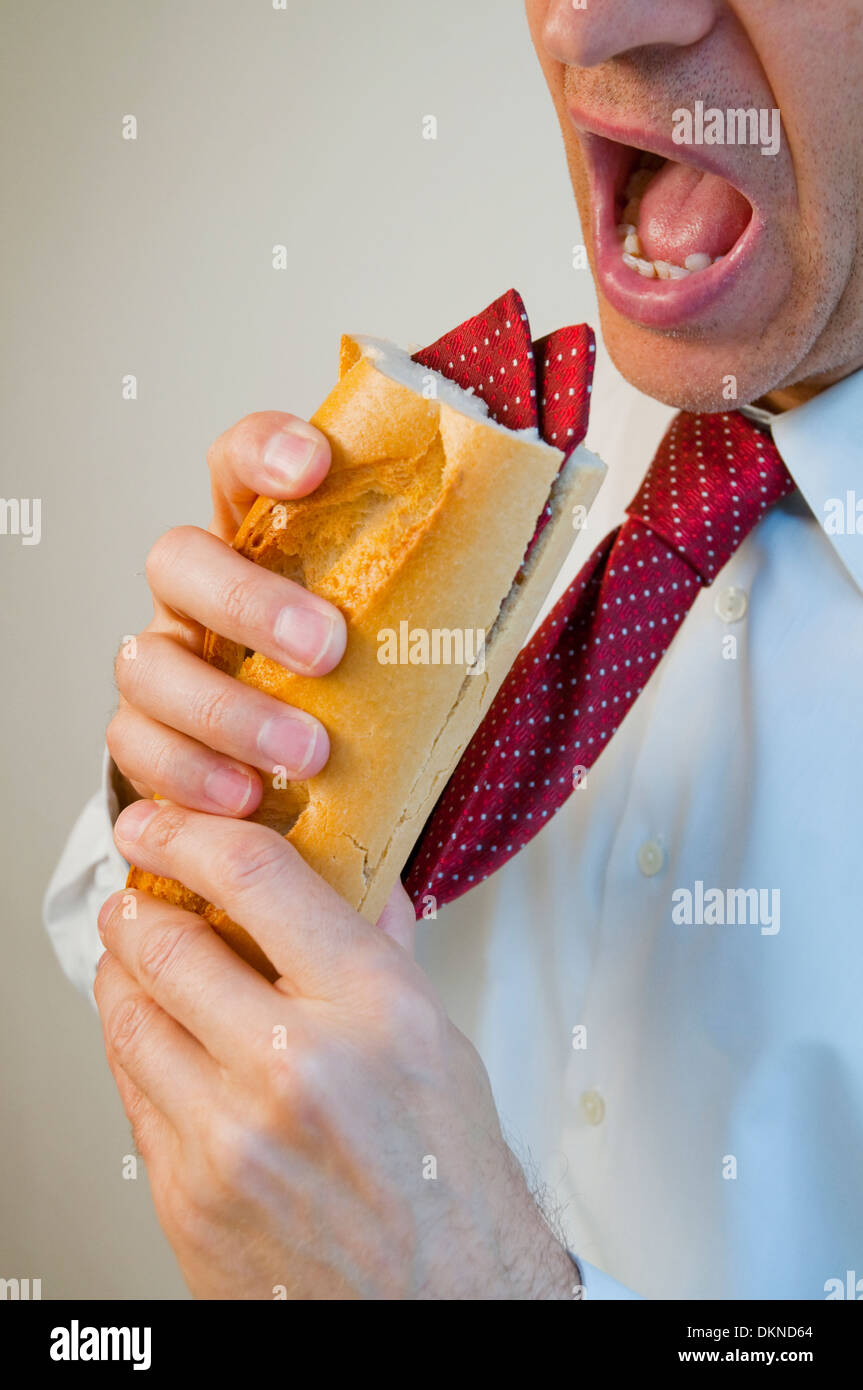 Man eating a sandwich made of his own tie. Stock Photo