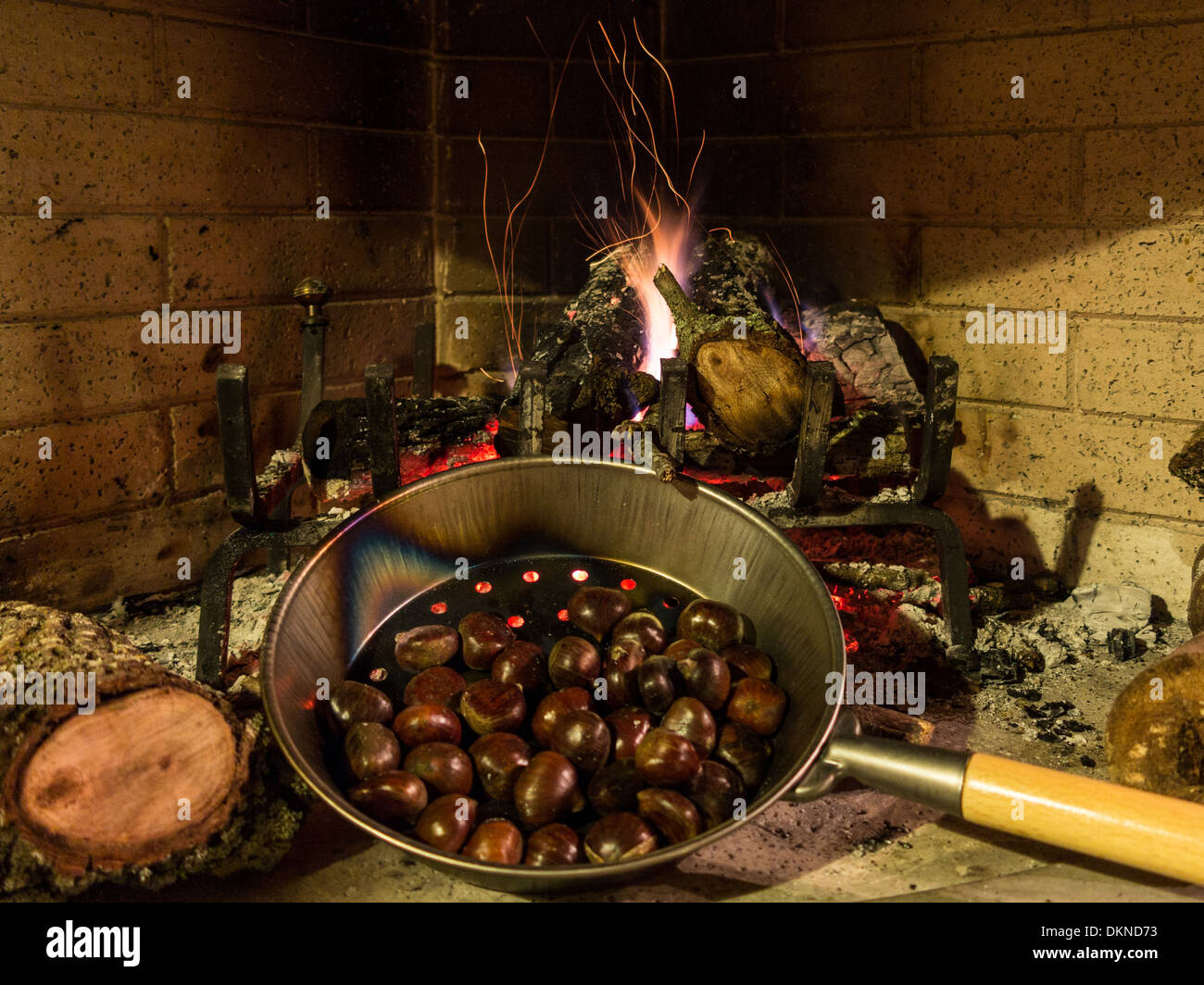 Chestnuts in a pan roasting on a glowing fire with flames and embers