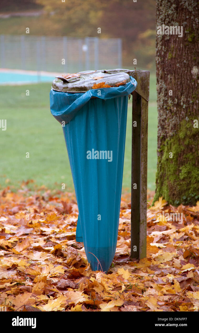 autumn scenery including a tree trunk, a small lake and a refuse sack Stock Photo