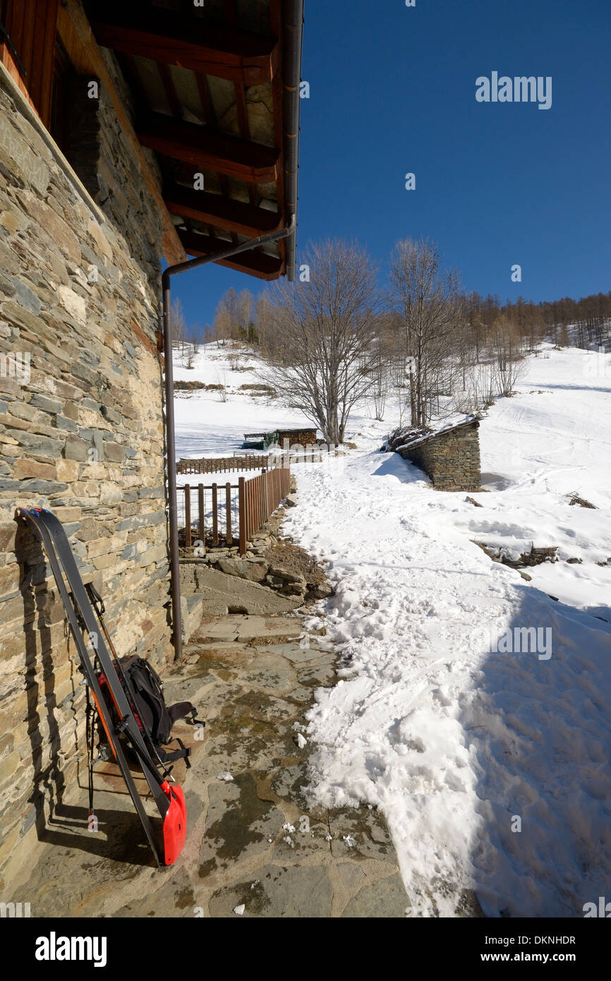 Pair of tour ski with backpack and light shovel for avalanche rescue on old stone wall of alpine hut in the italian Alps Stock Photo
