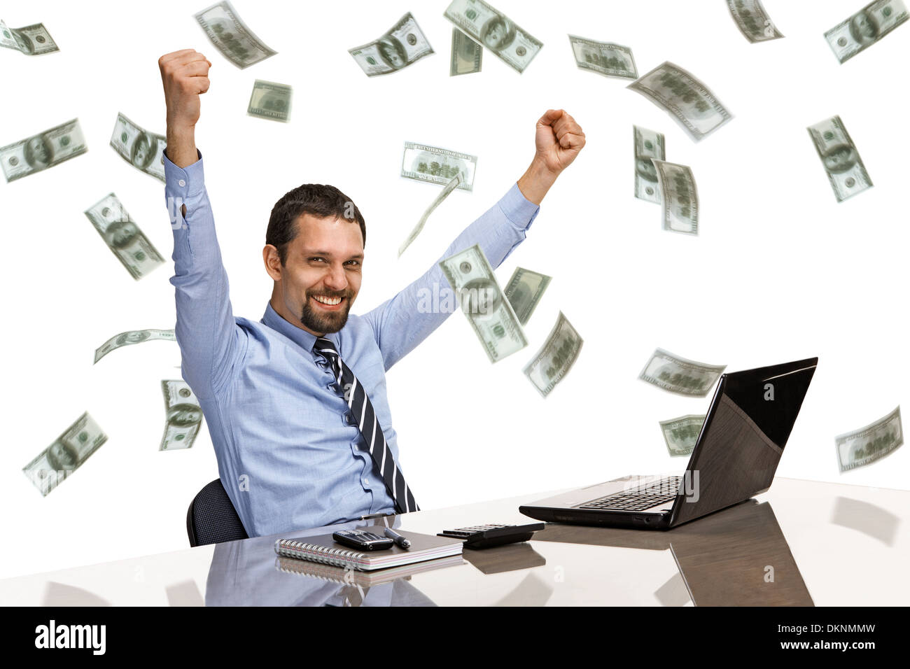 Businessman with his hands raised while working on laptop with money rain Stock Photo