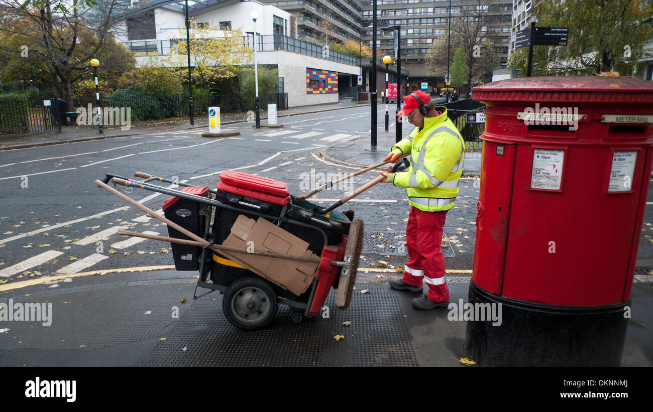Council worker street cleaner working outside in autumn and dustcart next to a red postal box in Golden Lane London EC2Y England UK  KATHY DEWITT Stock Photo