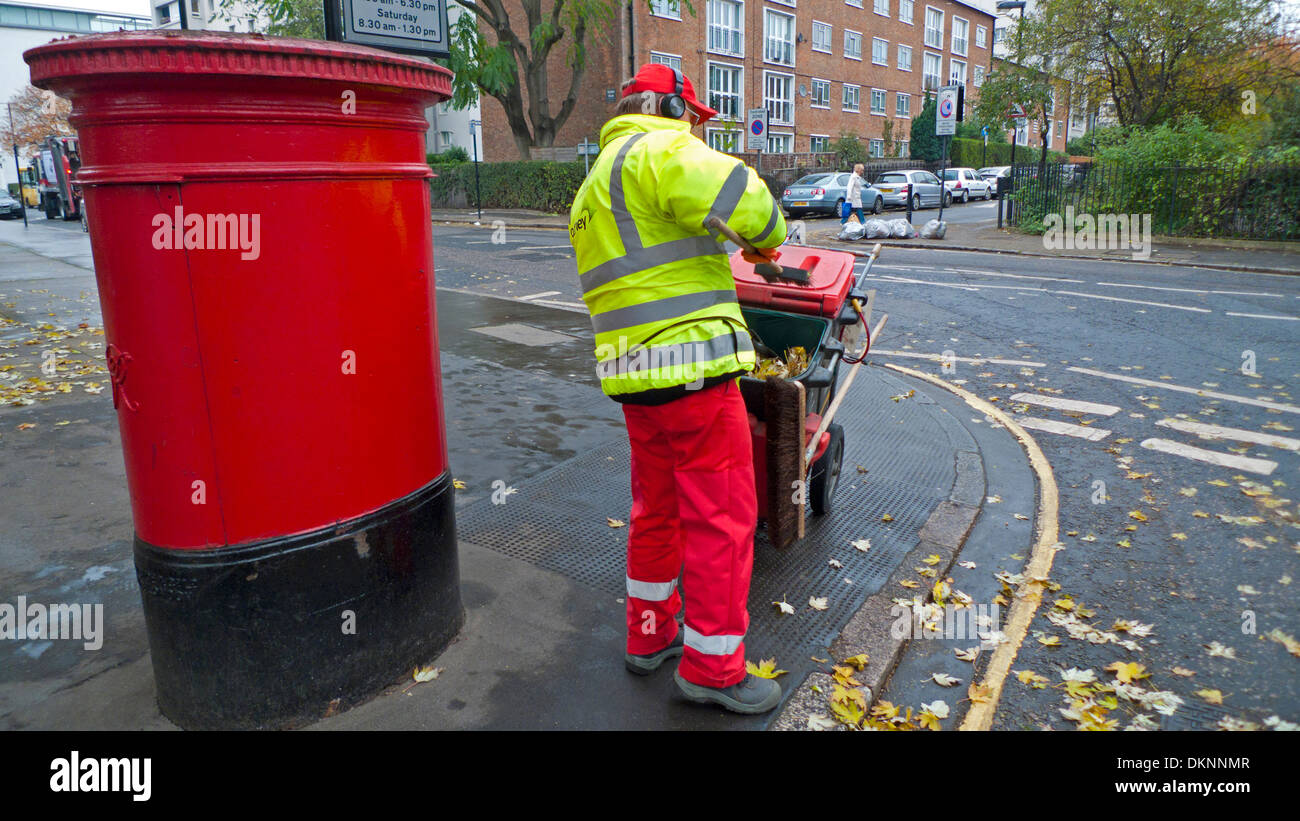 Street cleaner council worker working outside with a broom and dustcart next to a red postal box in Golden Lane London EC2Y England UK   KATHY DEWITT Stock Photo