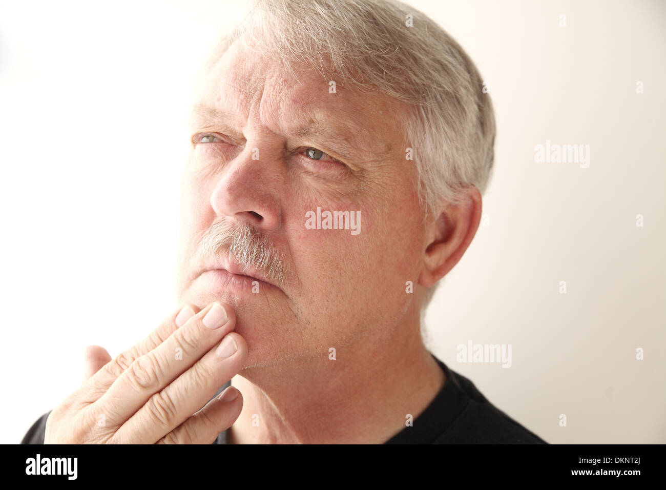 older man with fingers on chin and pensive expression Stock Photo