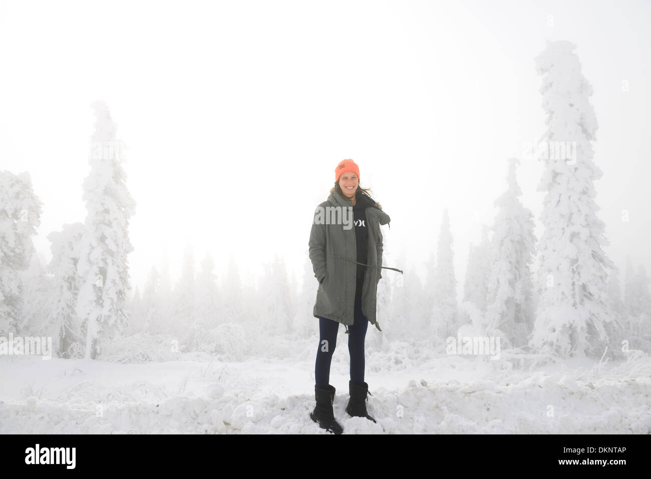 Female tourist on a snowbank with snow covered trees and winter fog on the Dalton Highway Alaska USA Stock Photo