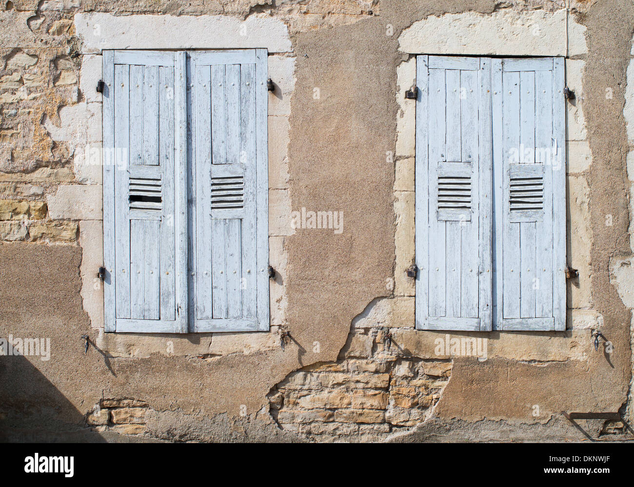 Closed faded blue shutters and crumbling plaster on a house in Santenay, Burgundy, France Stock Photo