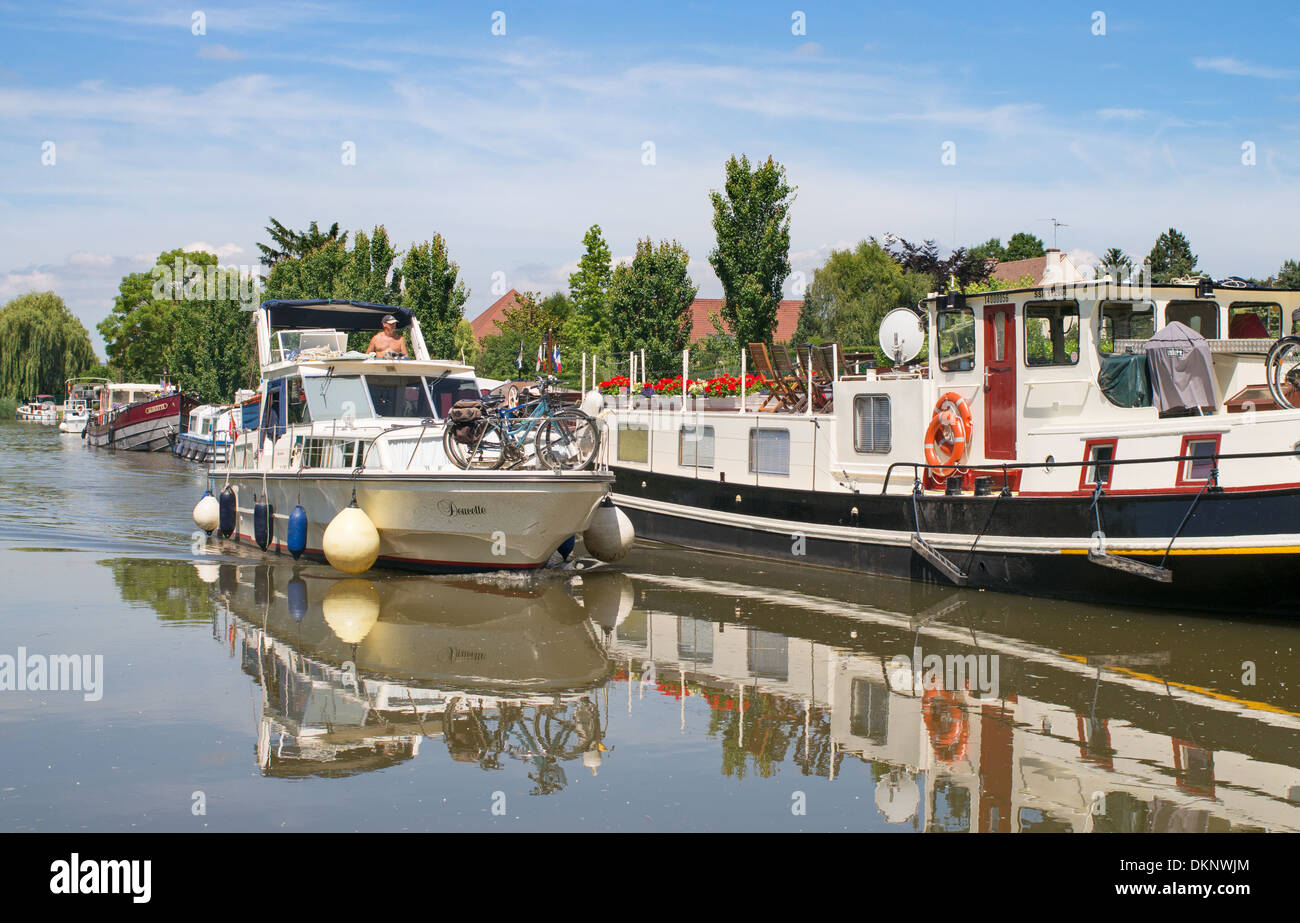 Canal cruiser passing moored boats Canal du Centre  Burgundy eastern France Stock Photo