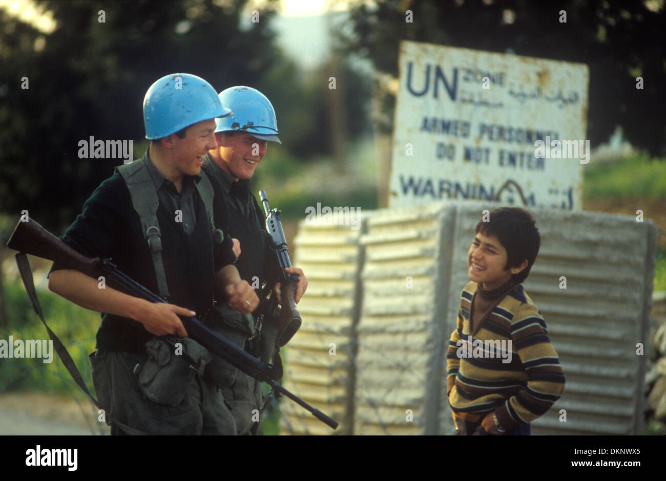 United Nations troops southern Lebanon 1980. UN 46th Irish Battalion wearing traditional blue helmets, two troops sharing a joke with a young Lebanese boy. 1980s HOMER SYKES Stock Photo