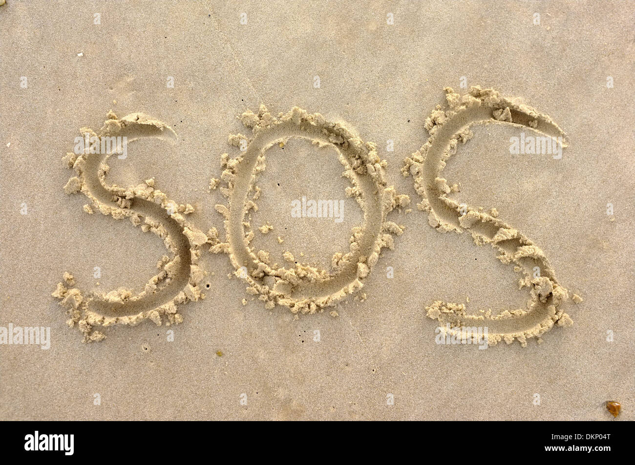 SOS 'Save Our Souls' sign symbol drawn in beach sand Stock Photo