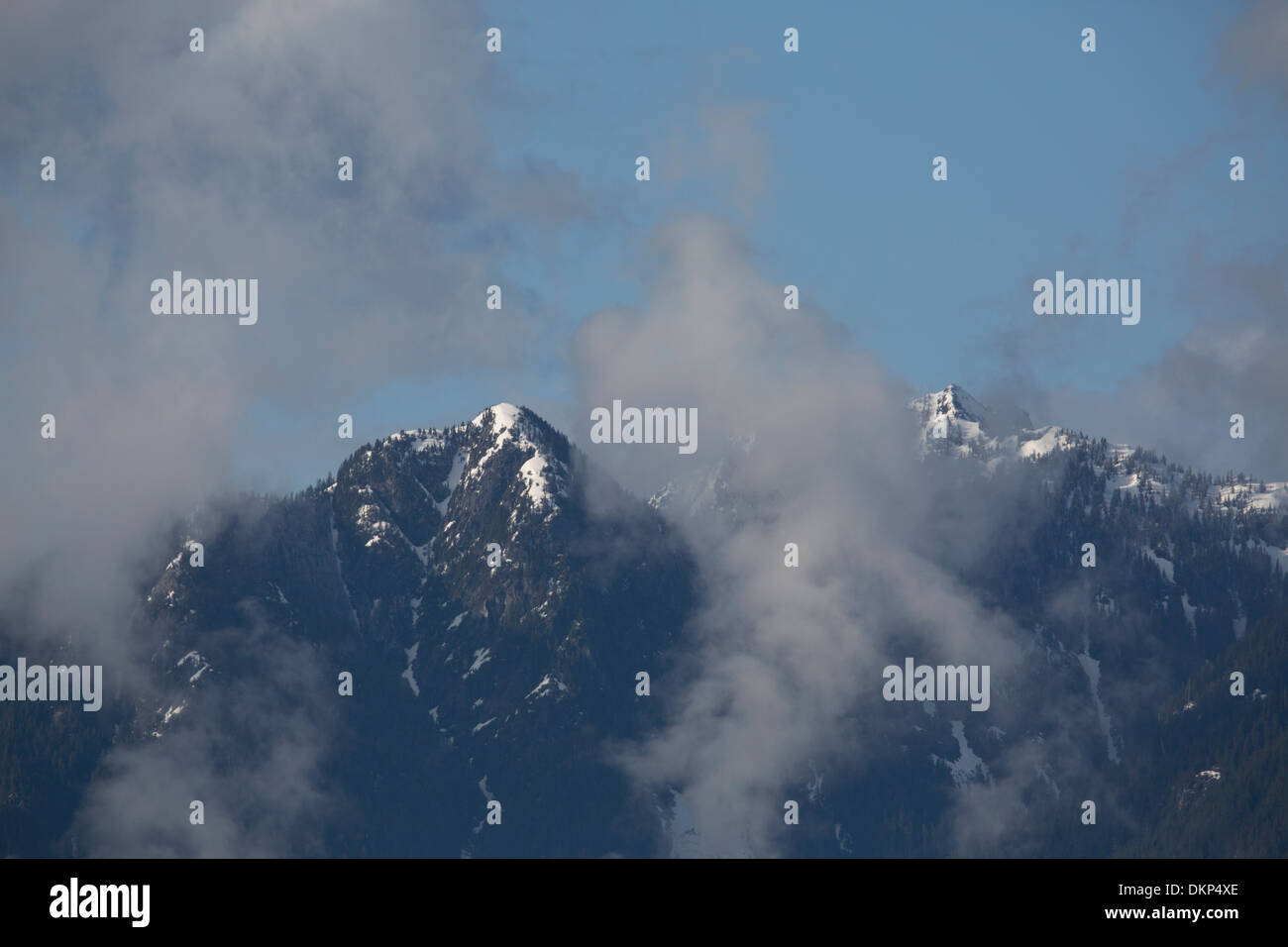 Snow-capped mountain peaks amid clouds in Vancouver, Canada. Stock Photo